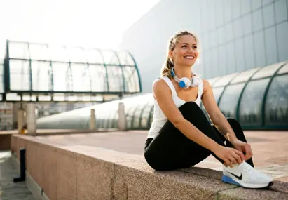 Vrouw in sportkleding strikt veters en draagt koptelefoon