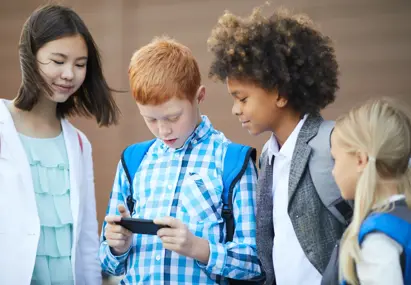 Vier jonge kinderen die samen kijken naar een telefoonscherm