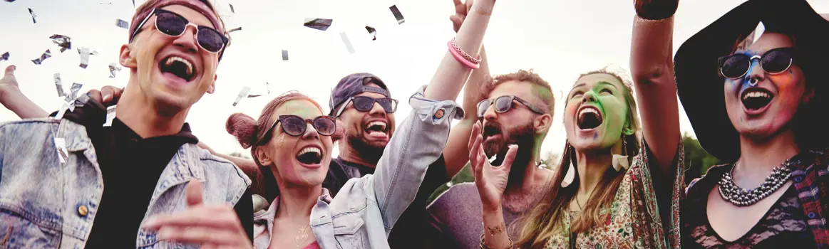 Groep vrienden lacht en strooit confetti tijdens festival