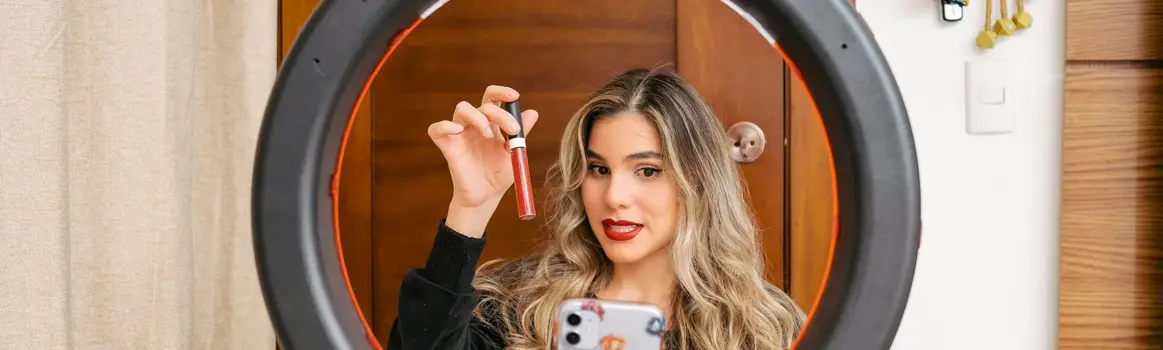 Vrouw laat lippenstift zien voor camera op standaard en ringlight