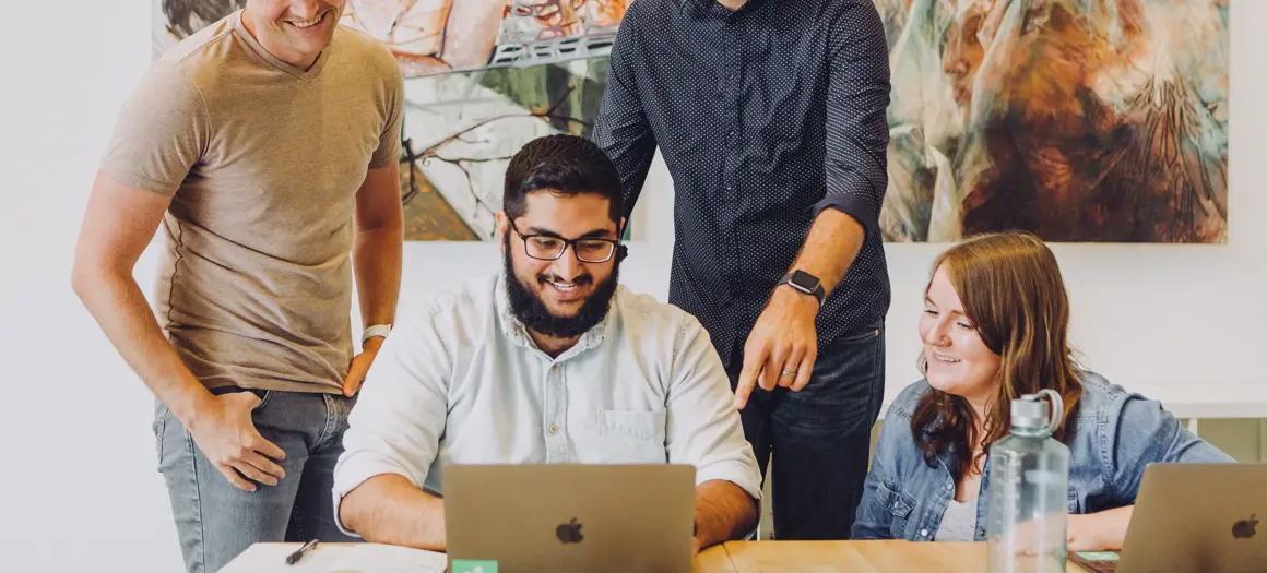 vier collega's lachend achter een laptop