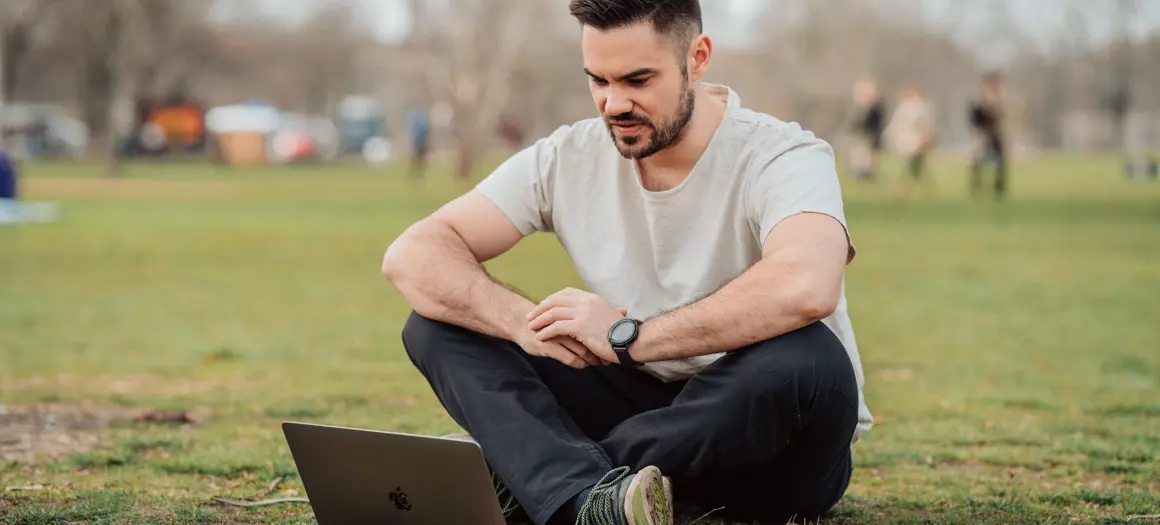 Jongen zittend op het gras met laptop