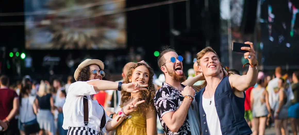 Vrolijke groep jongeren maakt een selfie op een zomers festival vol muziek, energie en merkbeleving