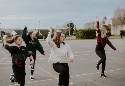 Vier dansende kinderen op een schoolterrein