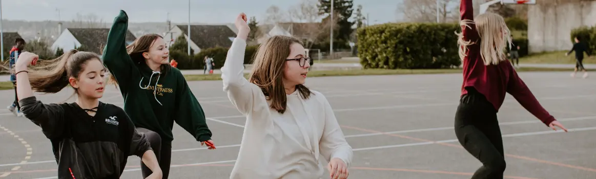 Vier dansende kinderen op een schoolterrein