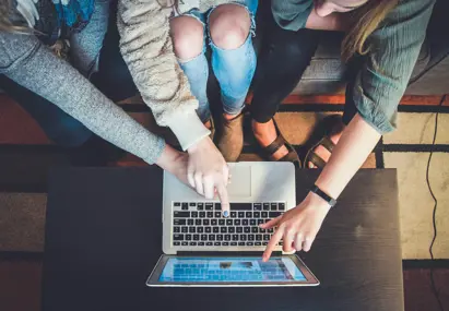 Verschillende personen kijken en wijzen naar een laptop
