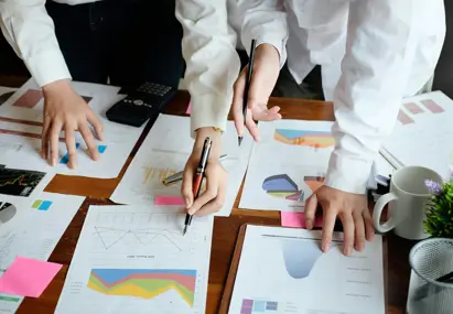 Twee personen kijken naar een tafel voor met papier met statistieken erop