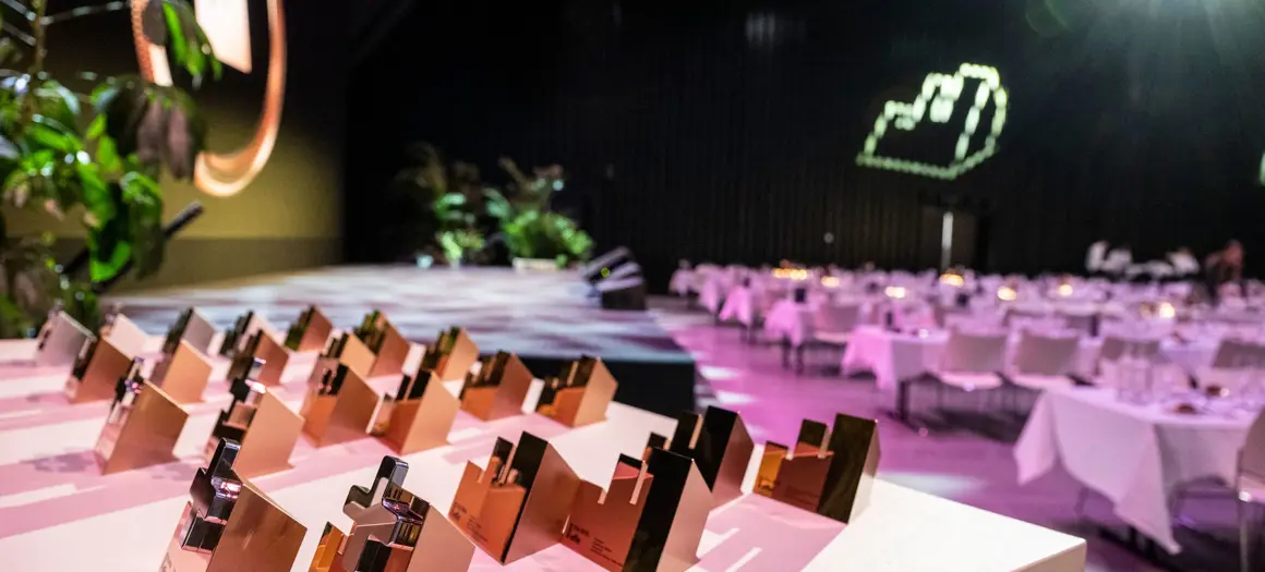 Tafel met alle effie awards erop gezet en op de achtergrond lege gedekte tafels