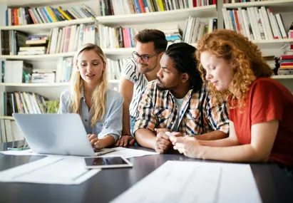 vieren personen aan tafel kijken samen naar een laptop