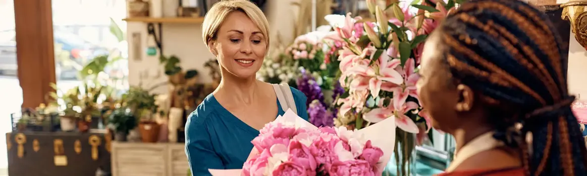 Vrouw koopt boeken met roze bloemen in winkel