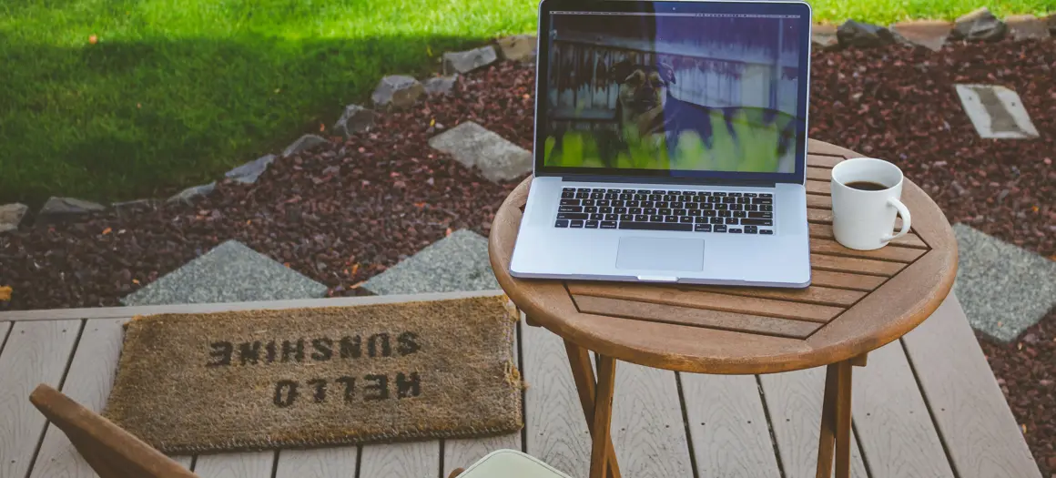 Tafel buiten met laptop en gras op de achtergrond