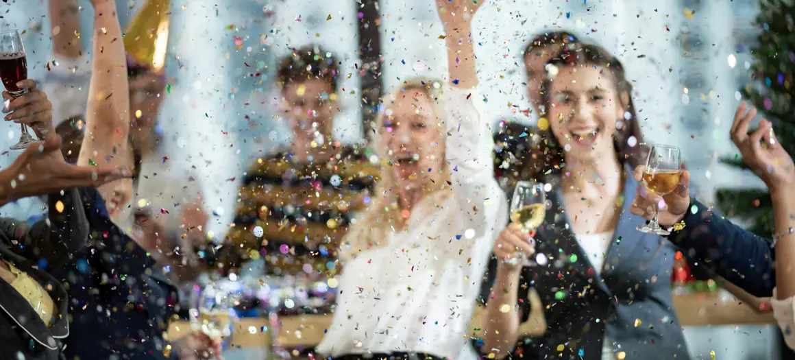 Collega's vieren succes op kantoor met confetti en champagne