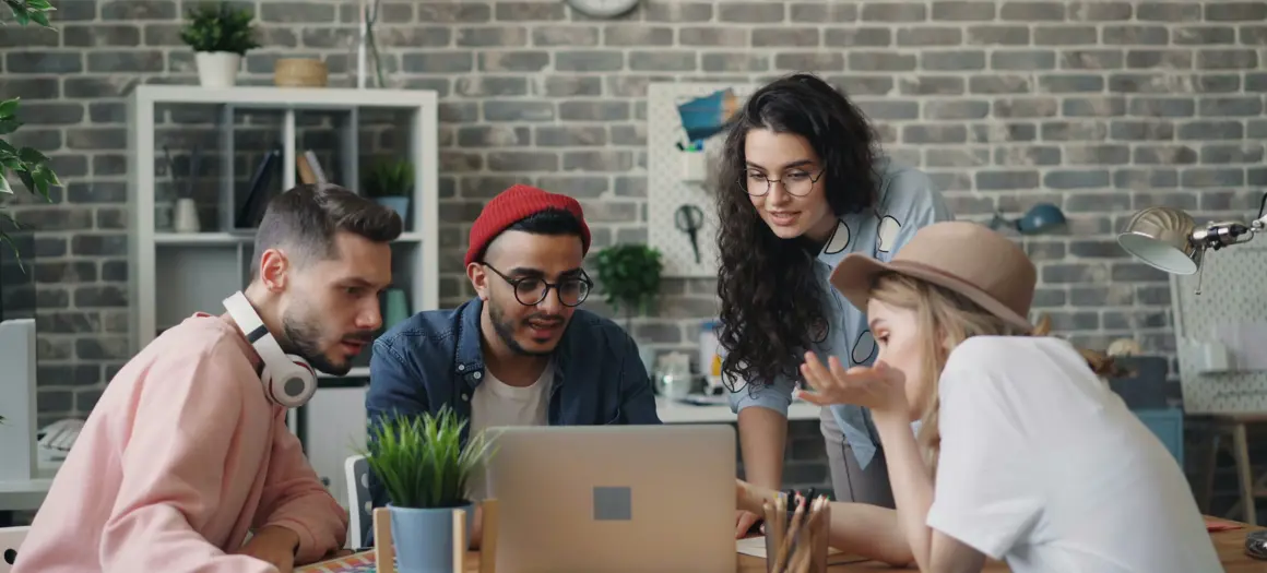Vier personen aan een tafel kijkend naar een laptop