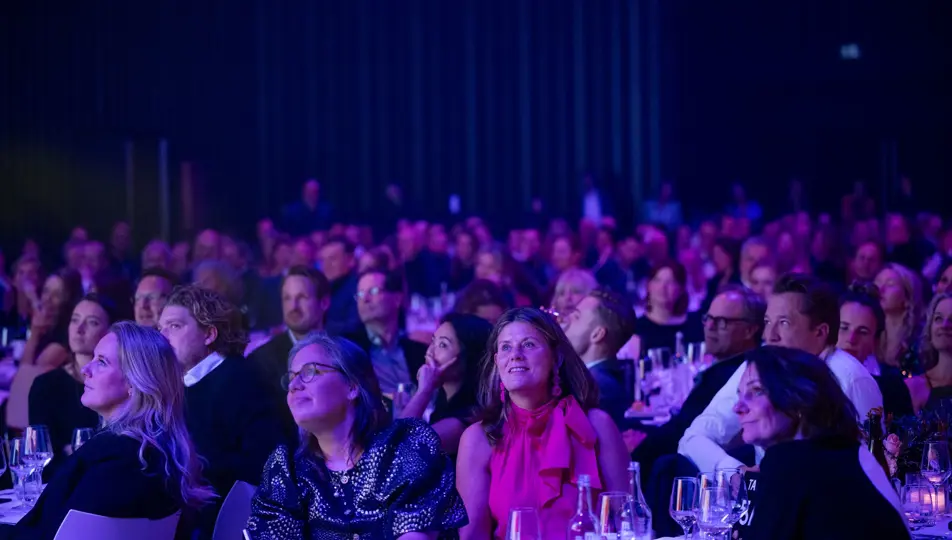 aanwezigen zitten aan tafel en luisteren naar presentator tijdens Effie Awards 2024