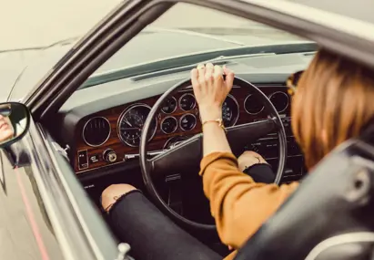 Vrouw achter het stuur in ouderwetse auto met radio