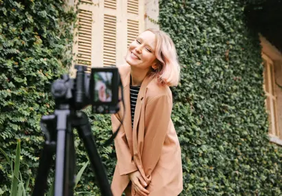 vrouw met bruin colbert poseert voor camera op standaard